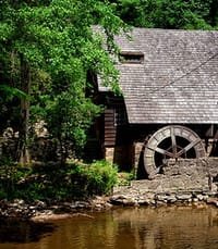Old watermill by a forested riverbank