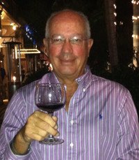 Man holding a glass of red wine, smiling.