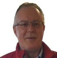 Smiling man wearing glasses and a red jacket.