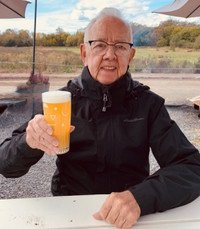 Person holding a beer outdoors on a sunny day.