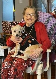 Elderly woman smiling with dog on her lap.